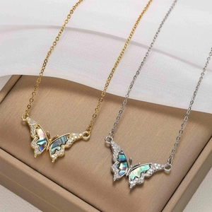 Macro detail of gold and silver butterfly pendants with shell inlay and zircons