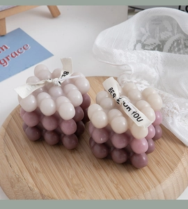 Close-up of gradient purple bubble cube candles on a wooden tray with lace details
