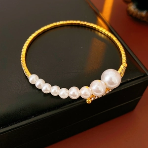 Close-up of elegant gold open cuff bracelet with gradient pearls and sparkling rhinestones
