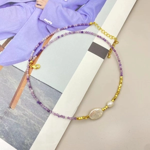 Detail view of purple tourmaline beads and baroque pearls on a gold-plated chain