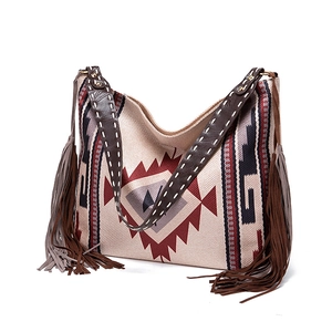 Detail of bohemian woven hobo bag featuring ethnic patterns and dark brown leather tassels