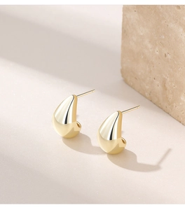 Macro shot of elegant golden teardrop earrings with a high-polished metallic finish