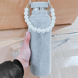Close-up of sparkling silver rhinestone tumbler with luxury pearl hand chain detail