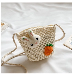 Dettaglio della borsa a secchiello in paglia con decorazioni di coniglio e carota