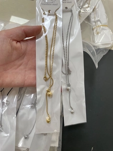 Detailed look at gold and silver stainless steel beaded tassel necklaces in hand