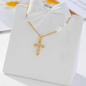 Detail of gold cross pendant with white zircon stones on a white jewelry stand