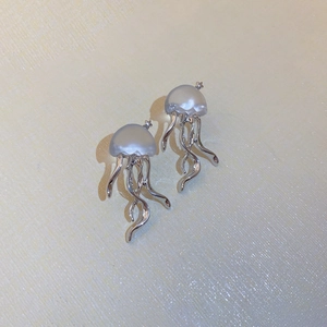 Détail macro de boucles d'oreilles méduse en résine translucide avec pompons argentés