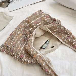 Detail of knit tote bag interior with magnetic clasp and pocket holding a smartphone