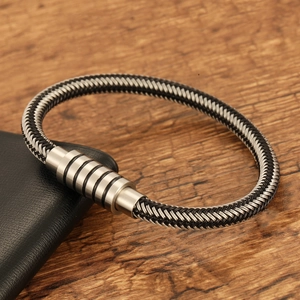 Detail of black and white woven fiber bracelet with cylindrical stainless steel magnetic clasp