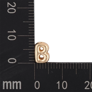 Macro shot of 10mm golden bubble letter B pendant showing precise size on a black ruler
