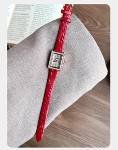 Dettaglio orologio rettangolare con cristalli e cinturino in pelle rossa motivo coccodrillo