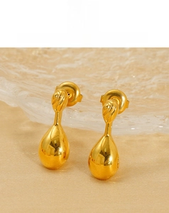 Macro view of teardrop titanium steel earrings with polished gold finish on fabric