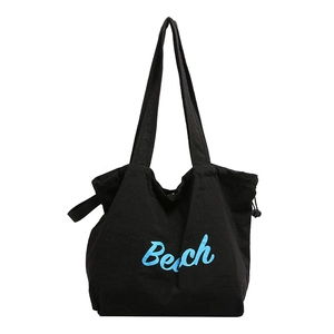 Black canvas tote bag with blue Beach print and drawstring sides for casual beach use