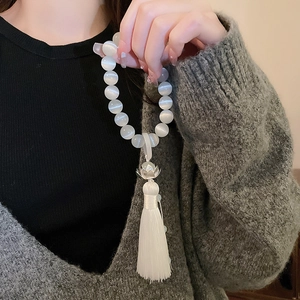 Detail of opal lotus flower bracelet with silky white tassel on model wrist