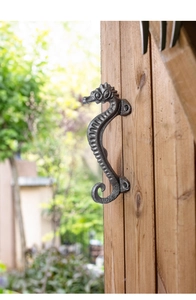 Close-up of vintage seahorse cast iron handle mounted on a light wood cabinet door