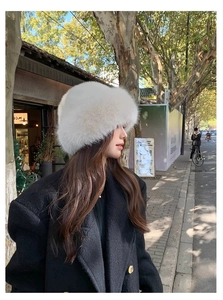 Detailed texture of white faux fur bucket hat shown on a model in autumn street