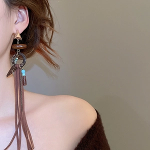 Detail of bohemian long tassel earrings with rose gold triangle and wood beads on model