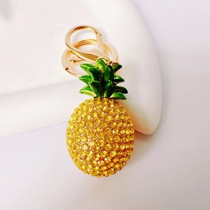 Close-up of sparkling yellow rhinestone pineapple keychain with green enamel leaf detail