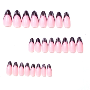 Almond-shaped press-on nails featuring a pink base with black French tips and white polka dots
