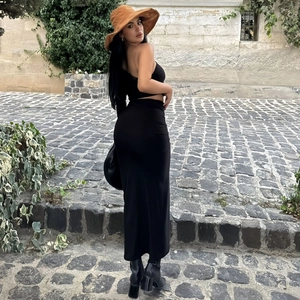 Rear view of woman in black backless halter top and high waist maxi skirt walking outdoors