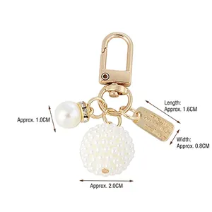 Golden pearl keychain with hollow heart pendant and rhinestone ring on white background