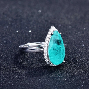 Macro view of pear-cut paraiba blue stone ring with micro-pave diamonds on black background