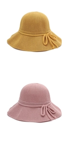 Detail of knitted sun hats in yellow and pink featuring elegant bow tie ribbons