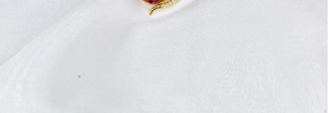 Close-up of red-orange teardrop pendant with small diamonds on gold-plated setting