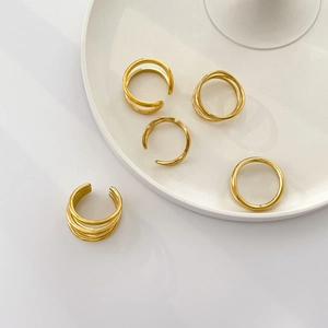 Detail of five-piece gold layered twisted rings and ear cuffs set on white ceramic