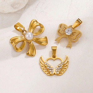 18K gold plated bow and heart pendants with pearls and crystals on stone background