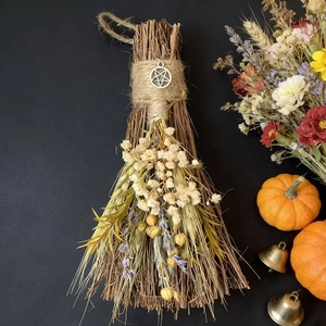 Detail of handcrafted twig broom with dried flowers, herbs and a silver pentagram pendant