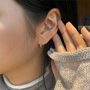 Close-up of minimalist silver geometric hexagonal hoop earring worn by a model