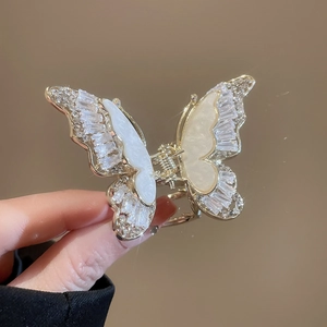 Dettaglio di un fermaglio a farfalla dorato con madreperla e accenti di zircone