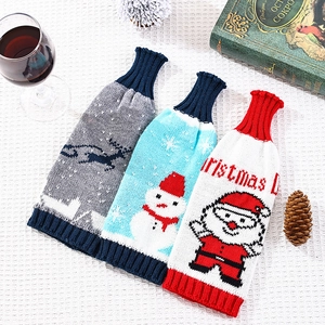 Détail de housses de bouteille de vin de Noël tricotées avec motifs Père Noël et élan