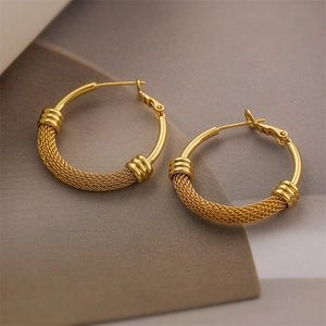 Detailed close-up of C-shaped golden earrings with a unique metal woven mesh texture