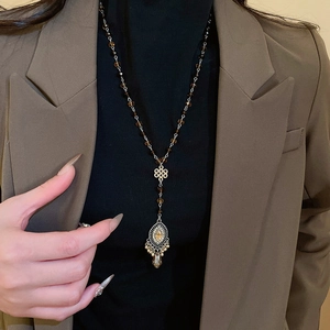 Detailed close-up of vintage long necklace with Chinese knot and brown crystal pendant