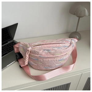 Detailed view of pink jacquard waist bag with colorful wave embroidery on white desk