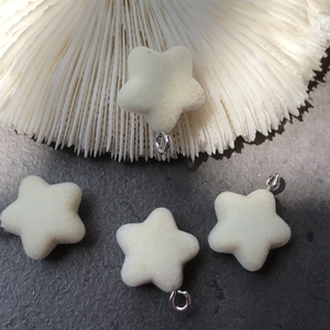 Close-up of cream flocked star pendants with metal rings for DIY jewelry making