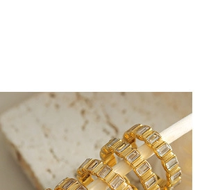 Macro shot of three gold rings with rectangular cubic zirconia on a white display rod
