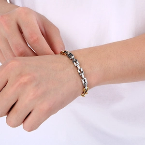 Primer plano de pulsera de cadena bicolor oro y plata lucida en la muñeca