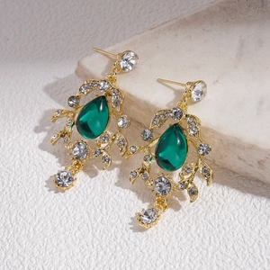 Detail von Luxus-Ohrringen mit grünem Edelstein und goldener Blattranken-Struktur