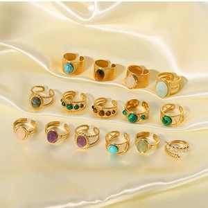 Detail of vintage 18k gold rings with emerald and turquoise stones on silk