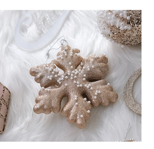 Close-up of champagne gold snowflake ornament with glitter coating and white beads