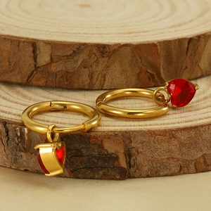 Elegant gold hoop earrings with red heart zircon charms on a natural wooden background