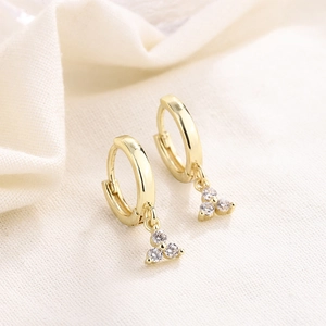 Macro shot of gold hoop earrings with three sparkling round-cut cubic zirconia stones