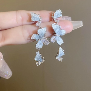 Detailed close-up of blue crystal butterfly dangle earrings with shimmering silver base