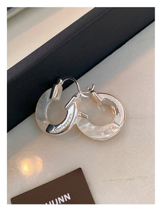 Detail view of silver metal hoop earrings with mother of pearl and Confession engraving