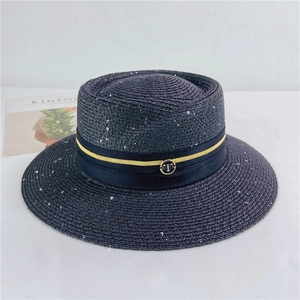 Close-up of a charcoal straw boater hat featuring a gold T-logo and glitter accents