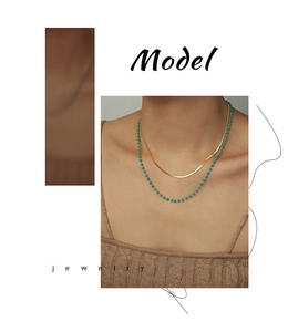 Detail of layered gold flat snake chain with turquoise beaded necklace on a female model