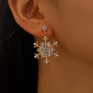 Close-up of gold snowflake earrings with sparkling rhinestones and small white pearls